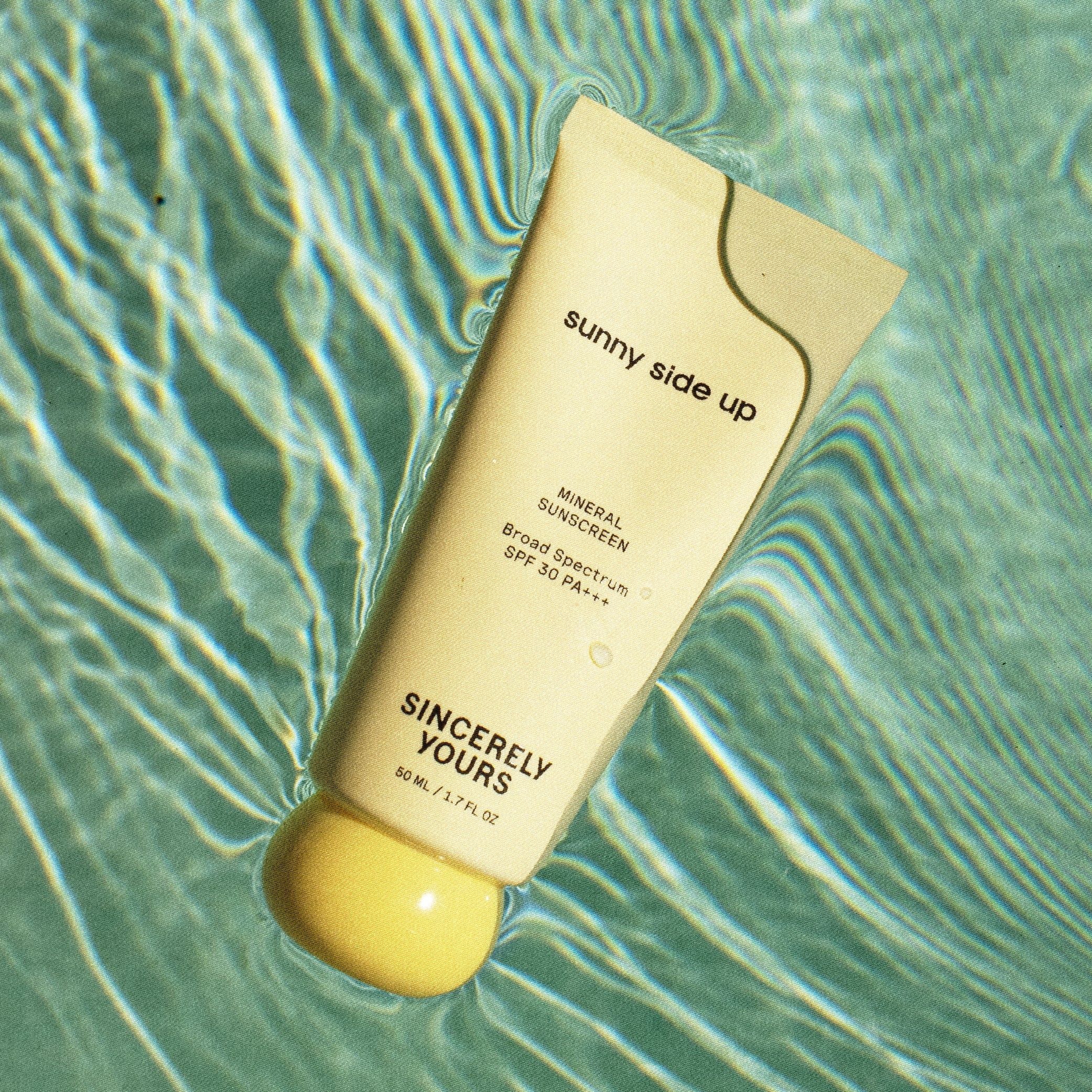Sunscreen bottle labeled 'sunny side up' on a water surface